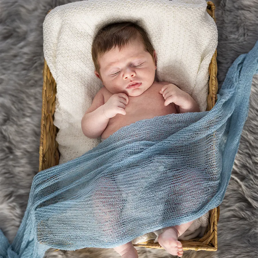 A peaceful newborn baby sleeping in a professional photography prop during a lifestyle session  with Winnipeg Newborn Photographer Jason Lee