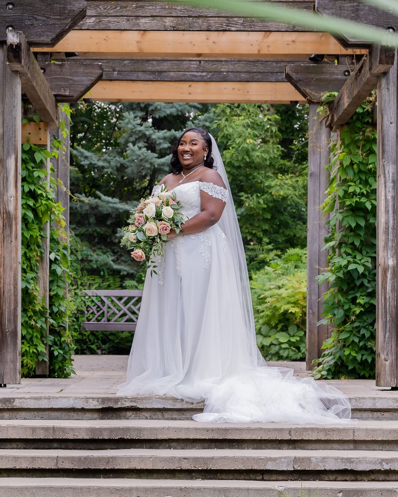 Bride portrait beneath the wooden pergola at Leo Mol Sculpture Garden