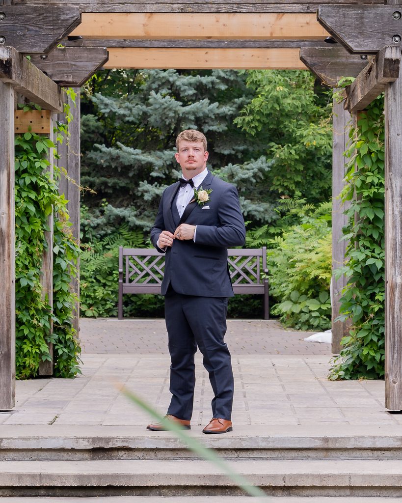 Groom portrait beneath the pergola at Leo Mol Sculpture Garden in Winnipeg