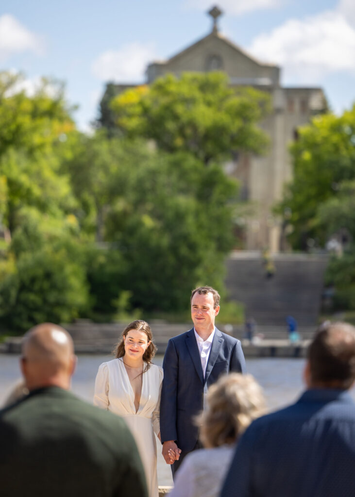 Bride and groom during their Red River wedding ceremony with St. Boniface Cathedral in the background