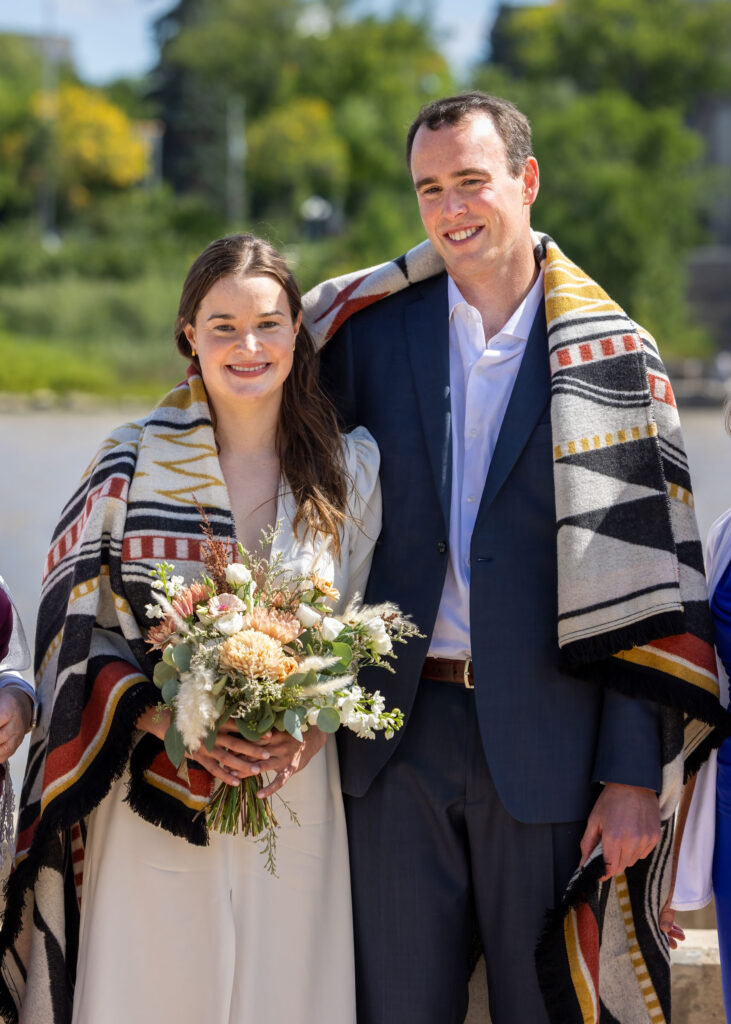 Bride and groom wrapped together during a Métis blanket ceremony at The Forks