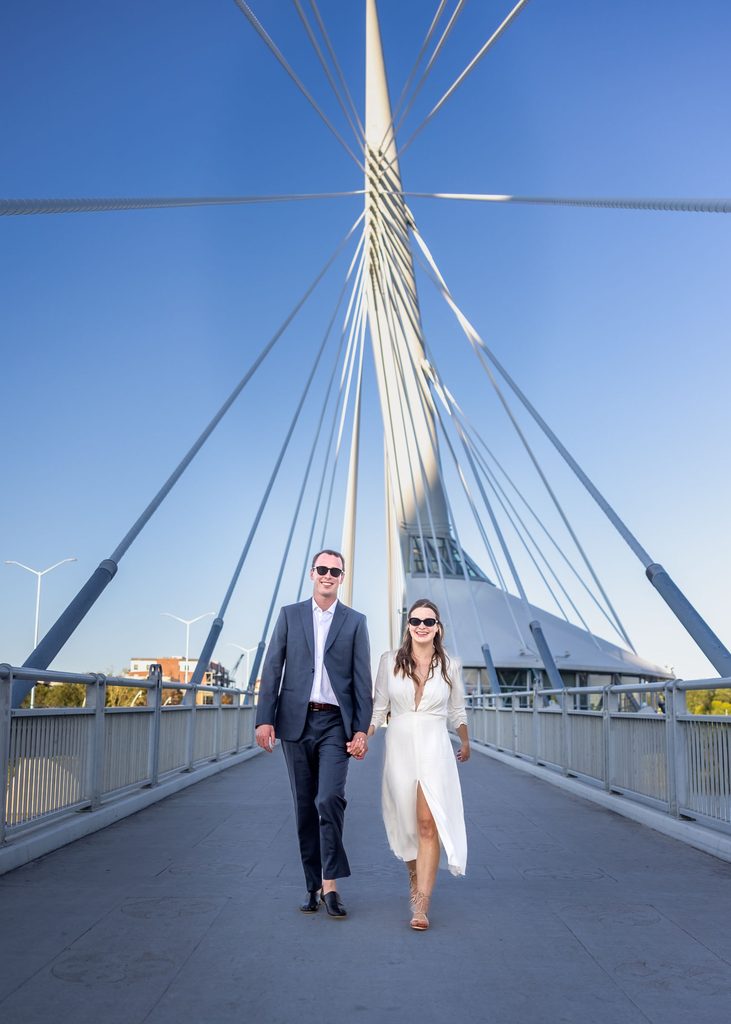 Bride and groom walking together on a pedestrian bridge near The Forks in Winnipeg