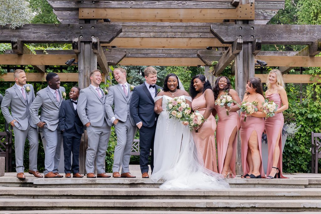 Wedding party laughing together at Leo Mol Sculpture Garden in Winnipeg