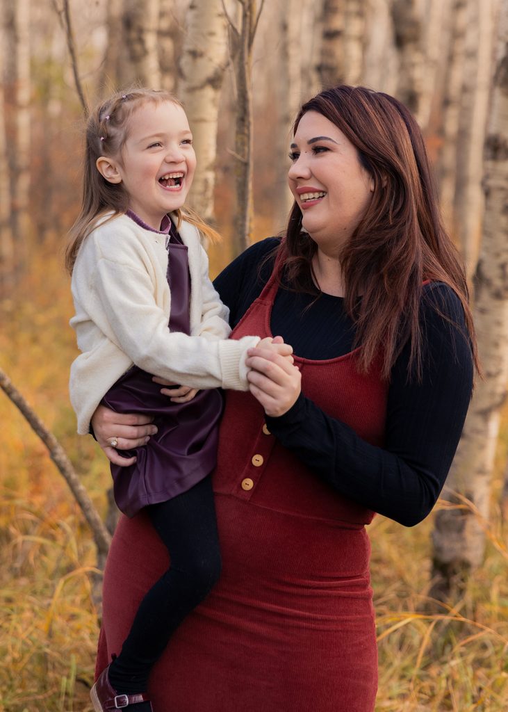 Mother and daughter laughing together during a fall family session at Assiniboine Forest