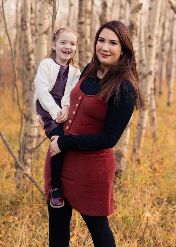Mother and daughter laughing together among the autumn birch trees in Assiniboine Forest