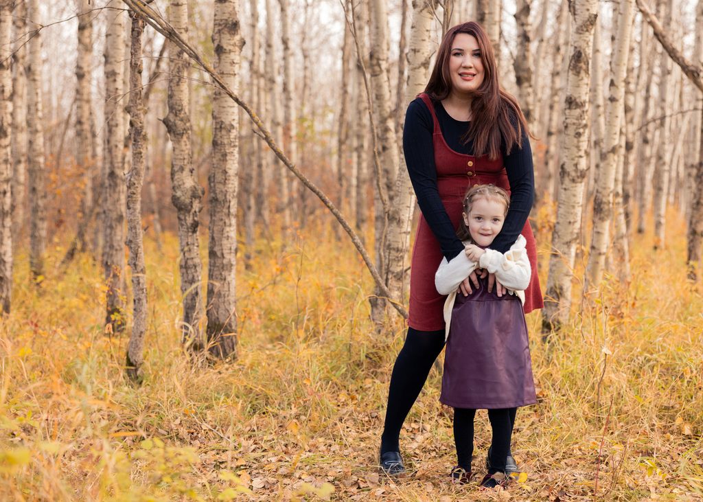Mother and daughter together among the birch trees and golden grasses of Assiniboine Forest