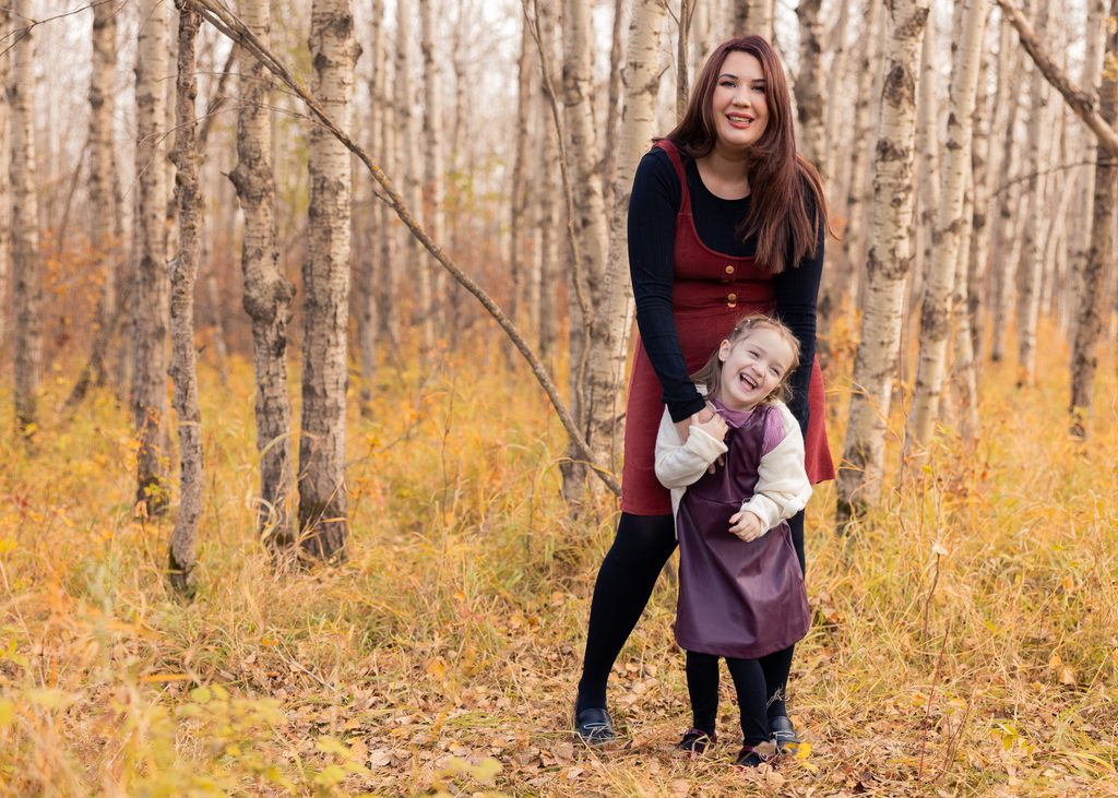 Mother embracing her daughter from behind during a playful fall family portrait