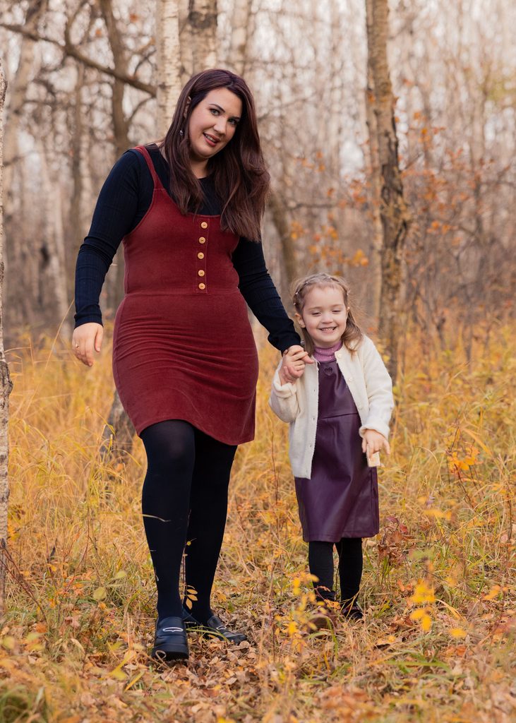 Mother and daughter walking hand in hand through Assiniboine Forest in autumn