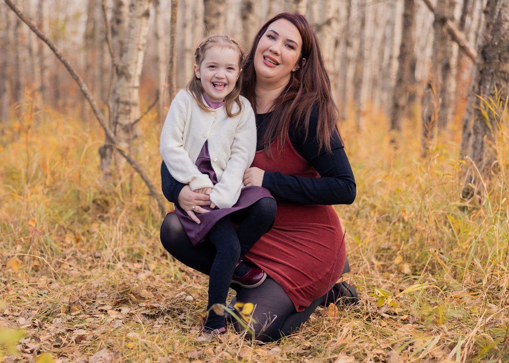 Mother and daughter laughing together during a fall family session in Assiniboine Forest in Winnipeg
