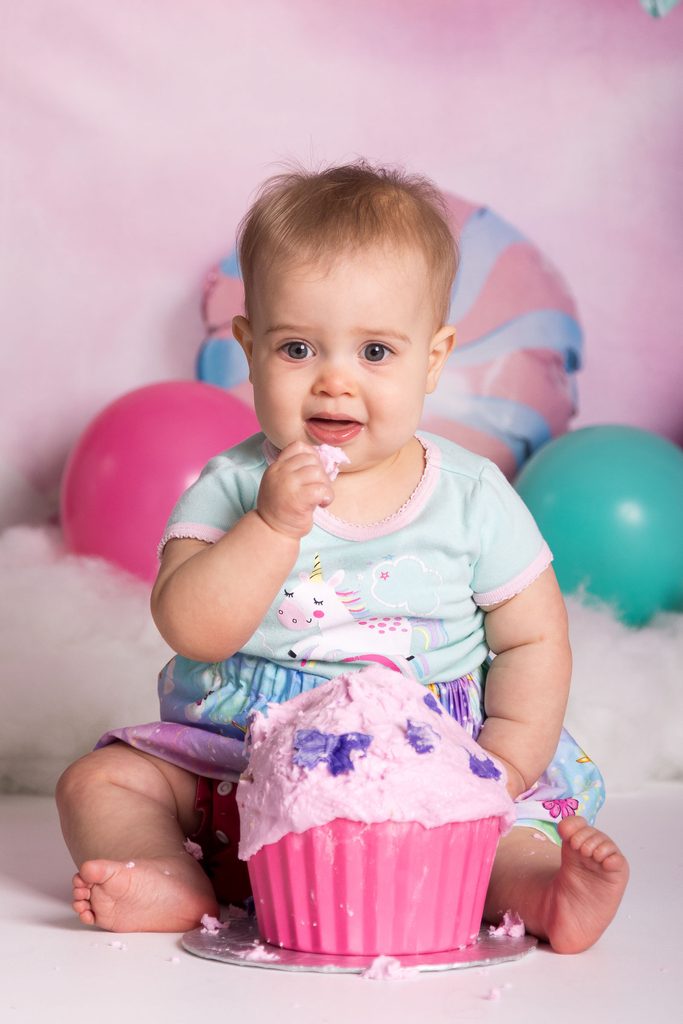 Baby tasting pink icing during a first birthday cake smash