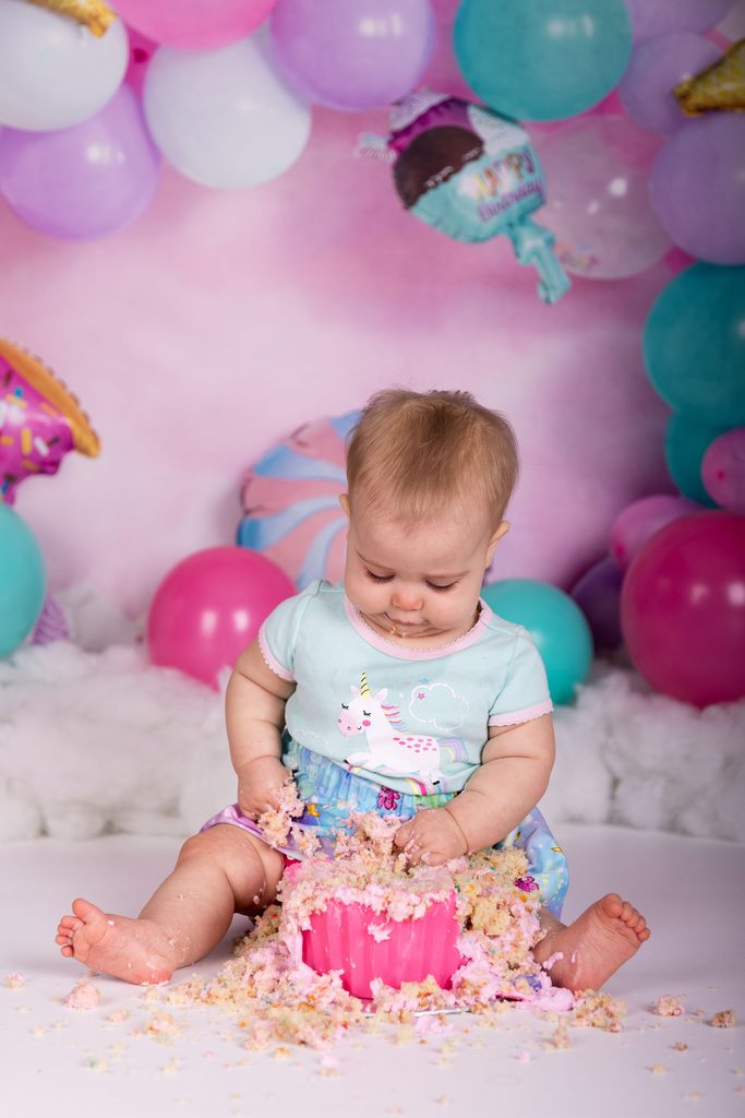 Baby exploring a smashed birthday cake during a studio cake smash