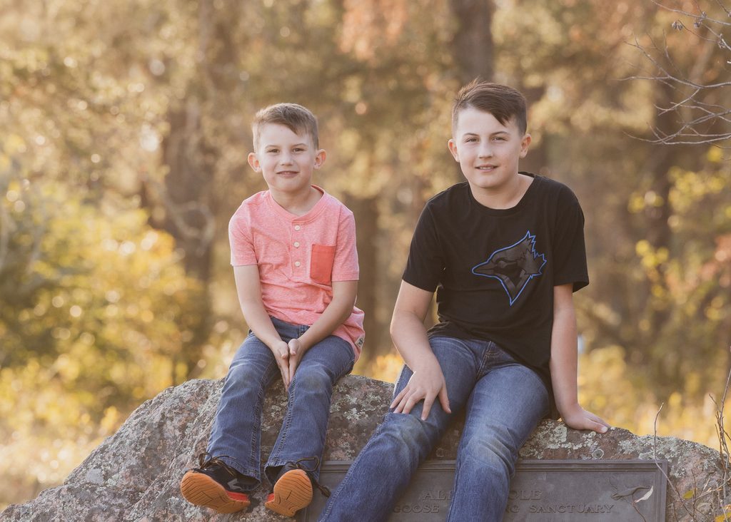 Siblings sitting on a large rock at Alf Hole Goose Sanctuary in Whiteshell Provincial Park