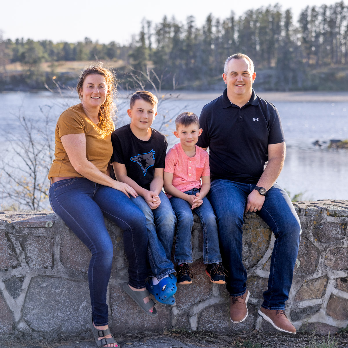 A family sits on the wall for their Fall Family Photo at the Alf Hole Goose Sanctuary in Whiteshell Provincial Park