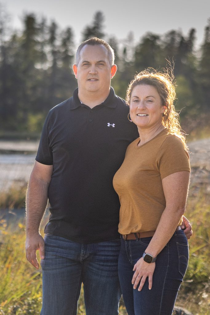 Couple standing together in warm autumn evening light during their family session