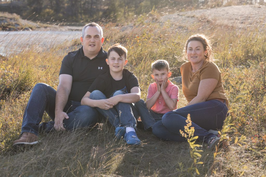 Family sitting together in autumn grass during a fall photography session in Whiteshell Provincial Park