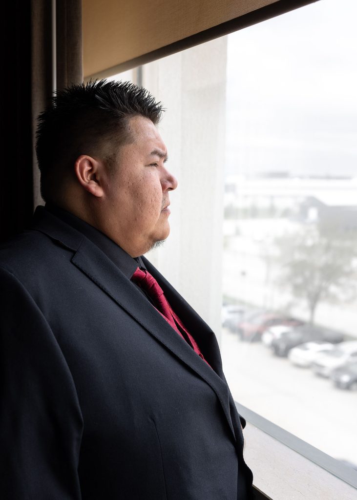 Groom looking out a hotel room window before his Winnipeg wedding ceremony
