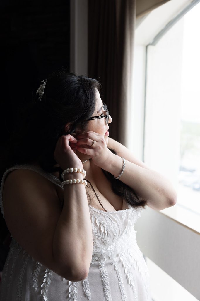 Bride putting on earrings during wedding preparations at the Victoria Inn