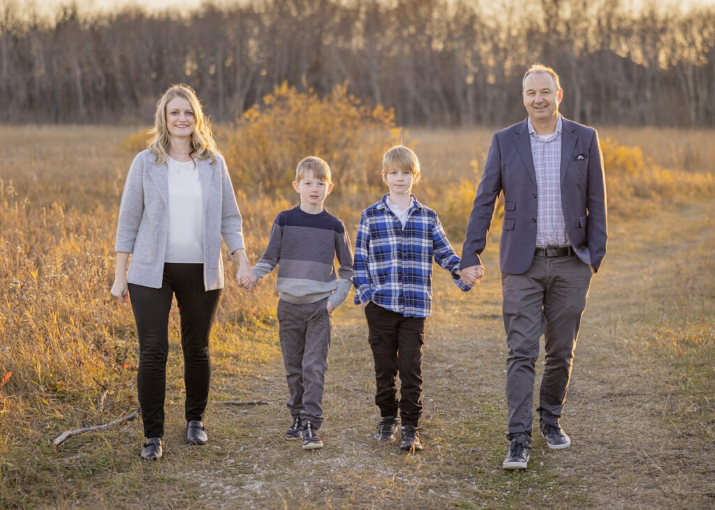 Family walking together through Assiniboine Forest during a fall photography session in Winnipeg