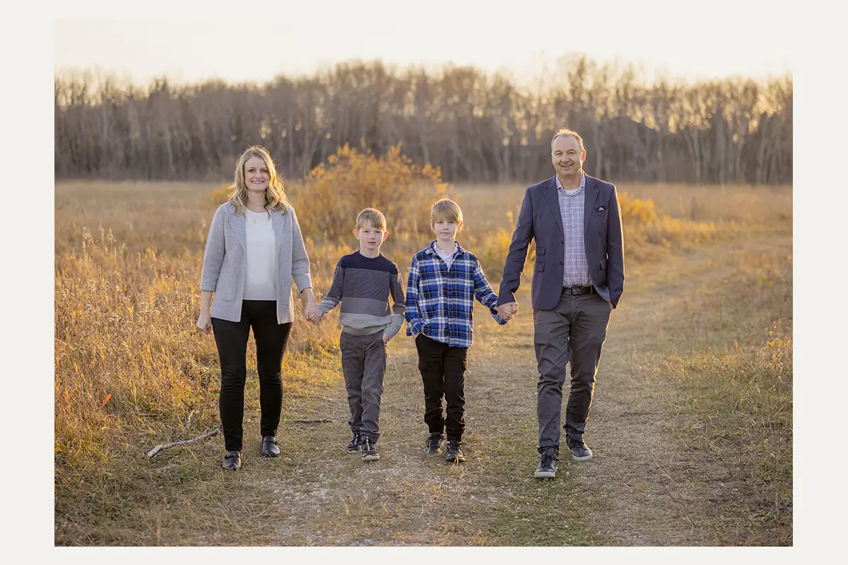 Family walking together through fall grass at Assiniboine Forest