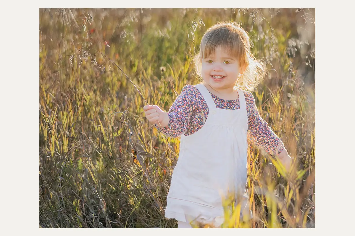 Young girl playing in tall grass during a fall family session at Beaudry Provincial Park
