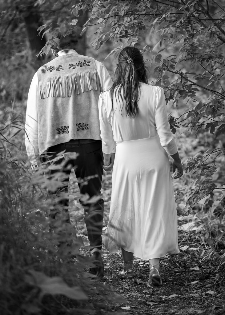 Black and white portrait of the bride and groom walking along a wooded path in South Point Park, Winnipeg.