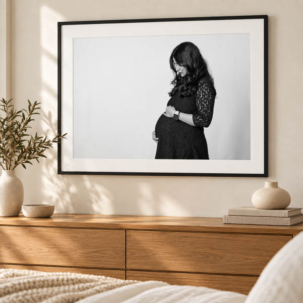 Framed black-and-white maternity portrait displayed above a wooden dresser.