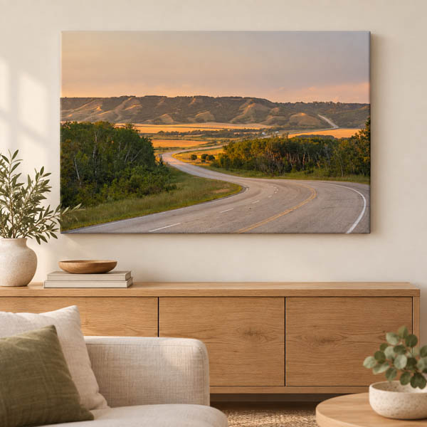 Canvas print of a winding road through rolling hills displayed above a wooden console.