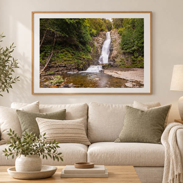 Framed Chute Jean Larose waterfall photograph displayed above a linen sofa