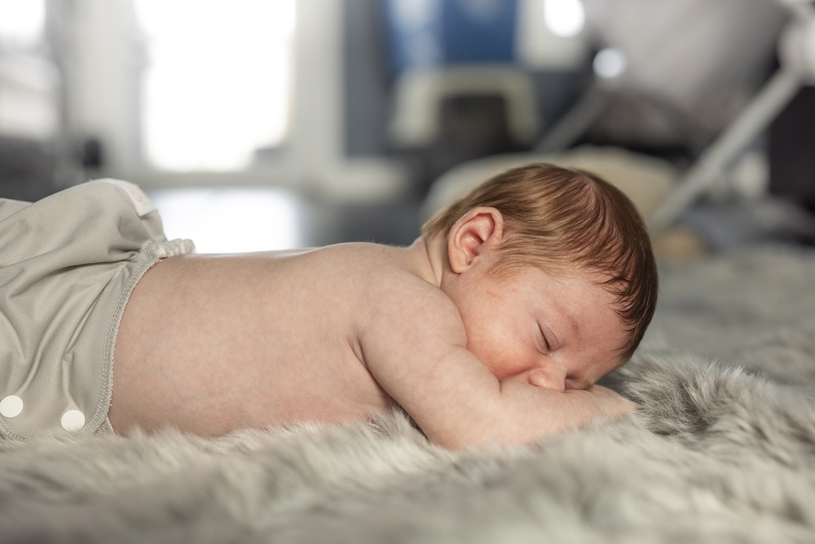 Sleeping newborn resting on a blanket at home.