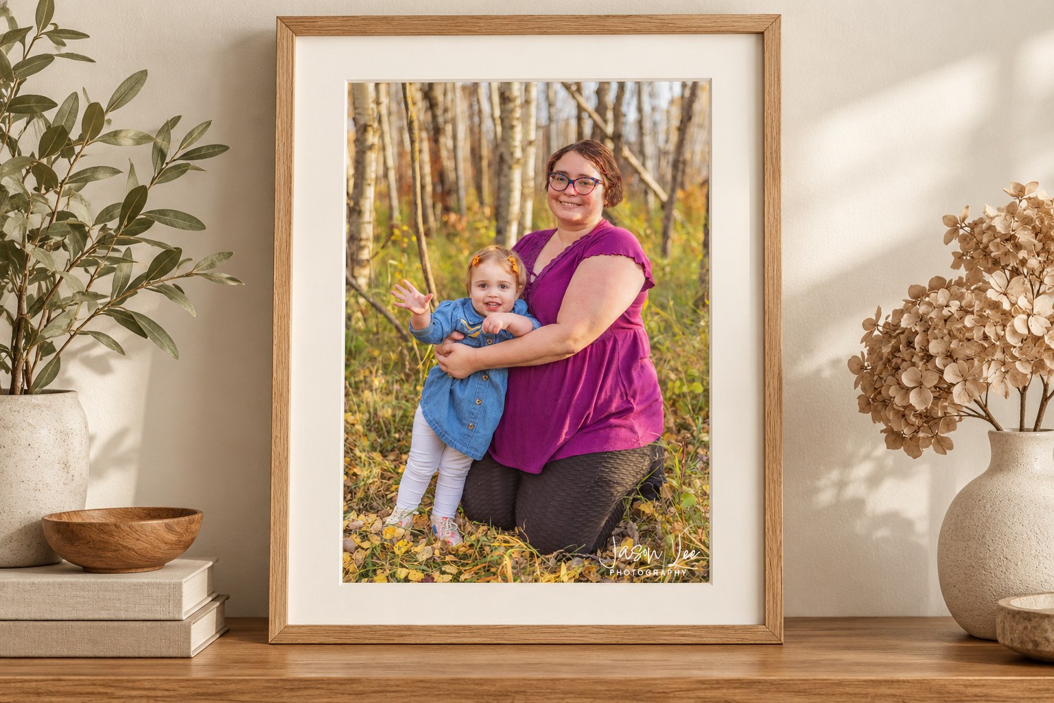 Mother-and-daughter portrait in an oak frame with a generous warm-white mat.