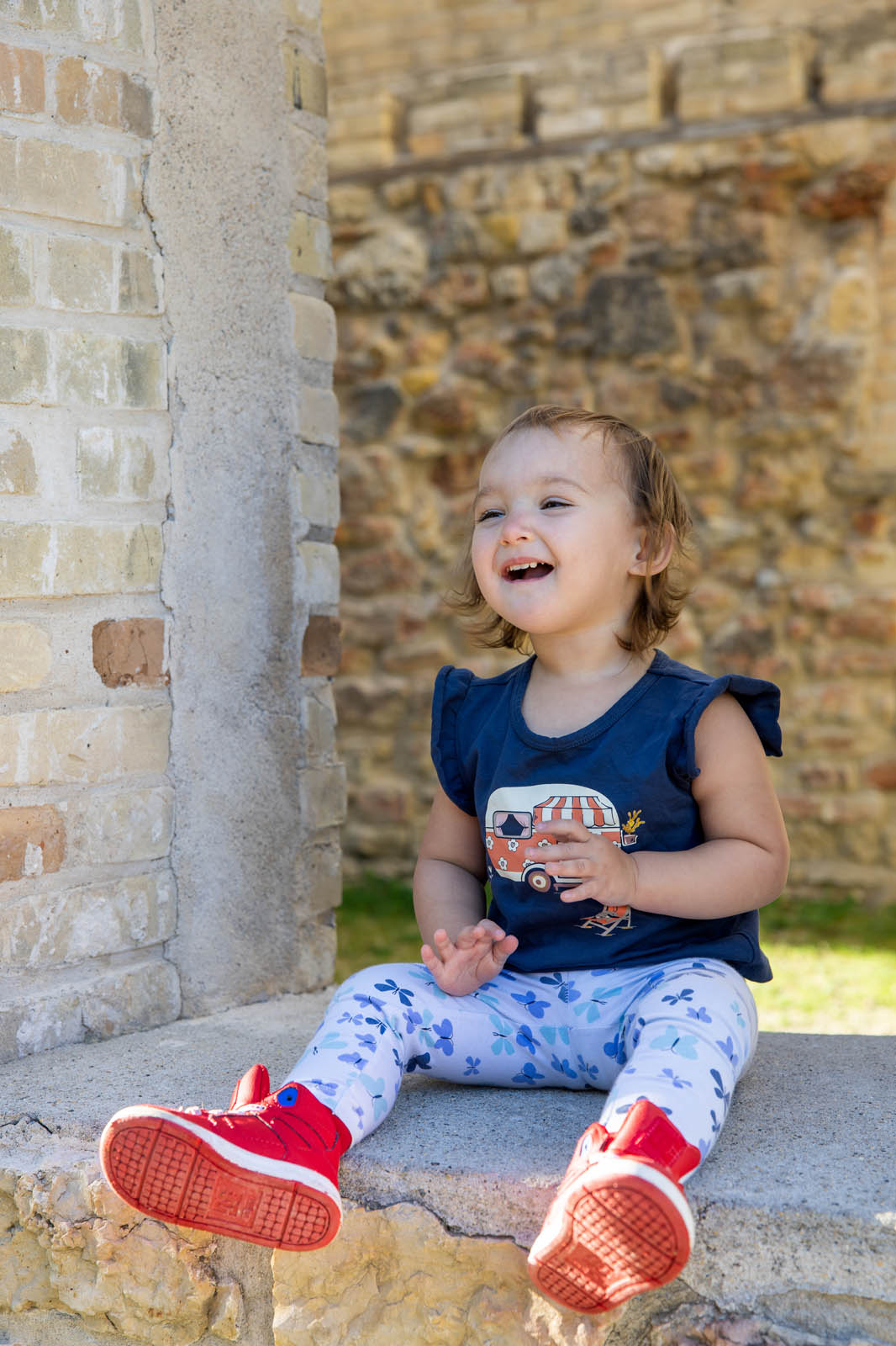 Youngest child looking upward and laughing while seated in a stone window.