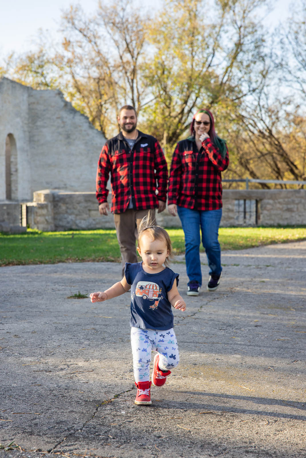 Young child moving toward the camera with parents in the background.