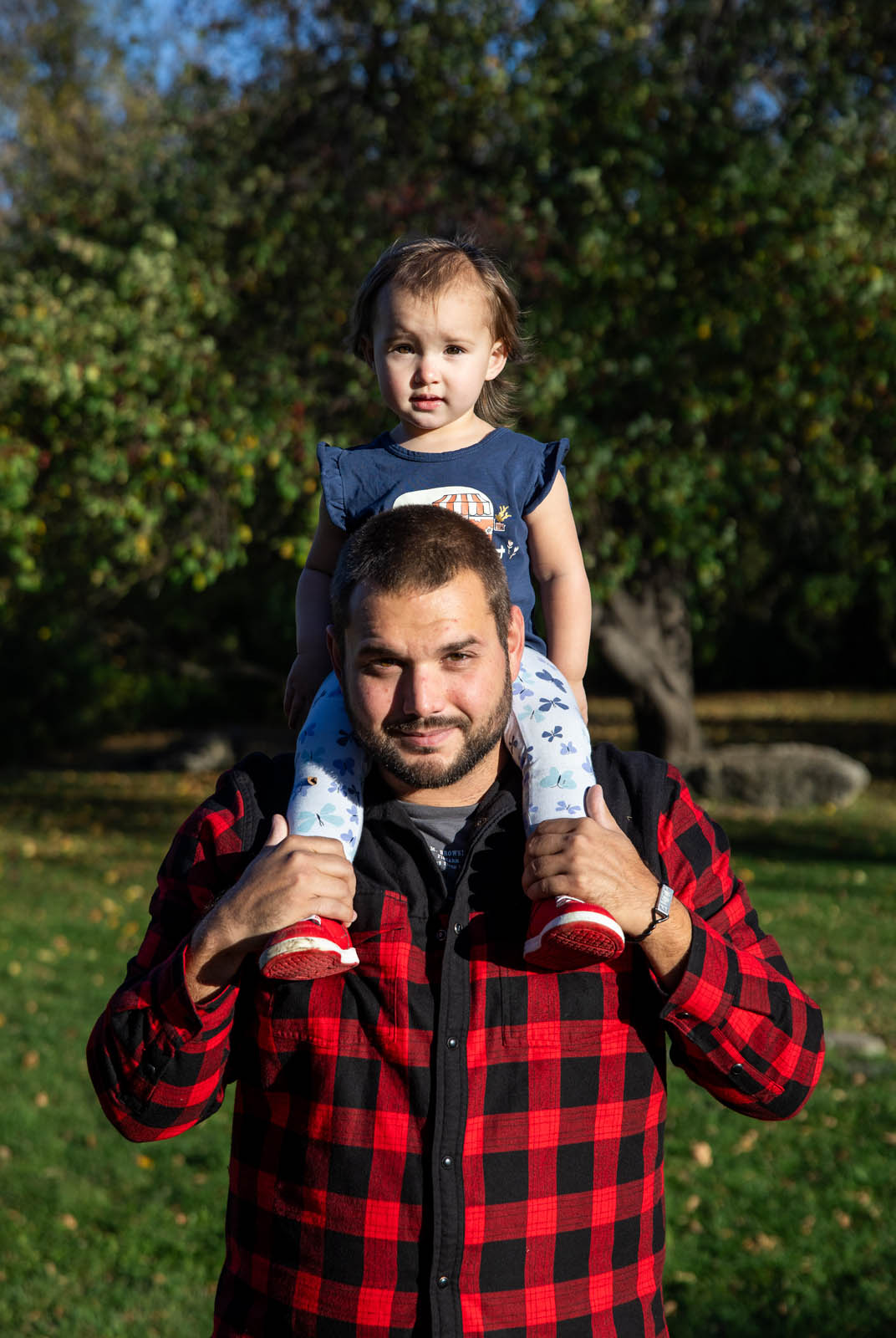 Father smiling with his youngest child sitting on his shoulders.