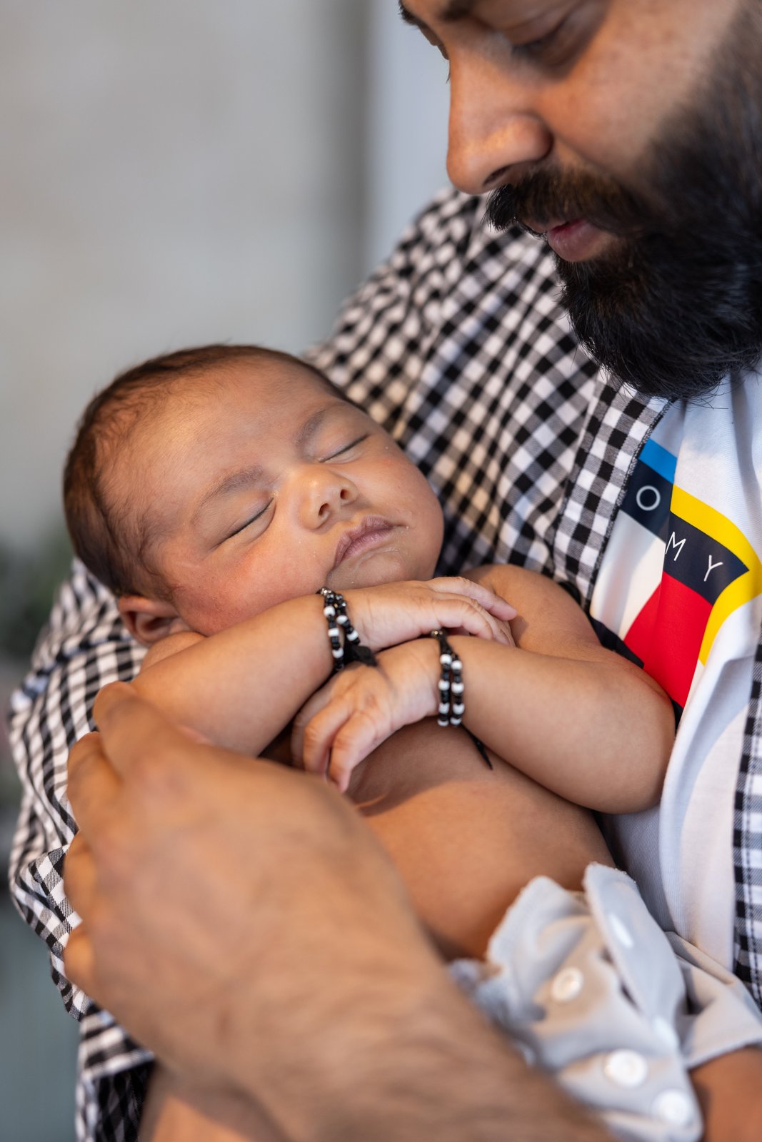 Father holding his sleeping newborn baby close to his chest.