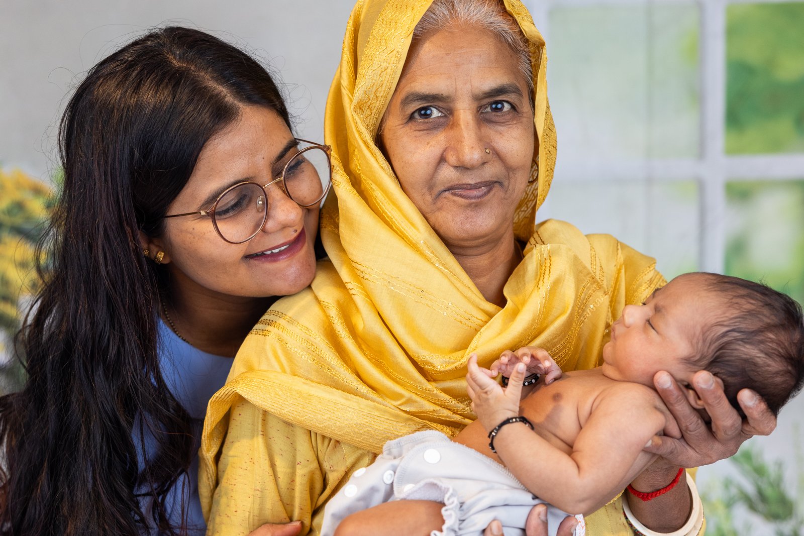 Two family members holding the newborn baby together.