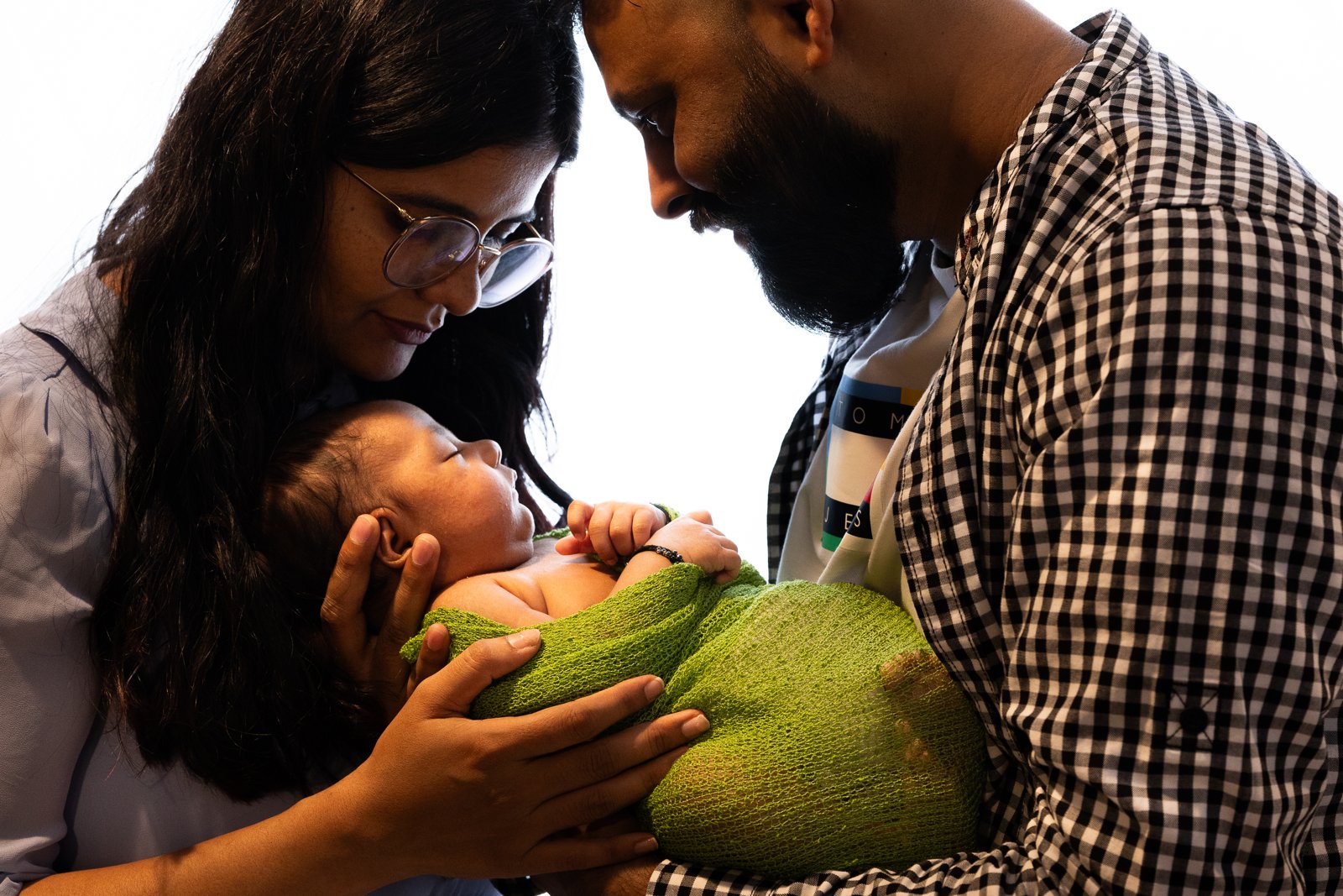 Parents looking down at their baby wrapped in green.