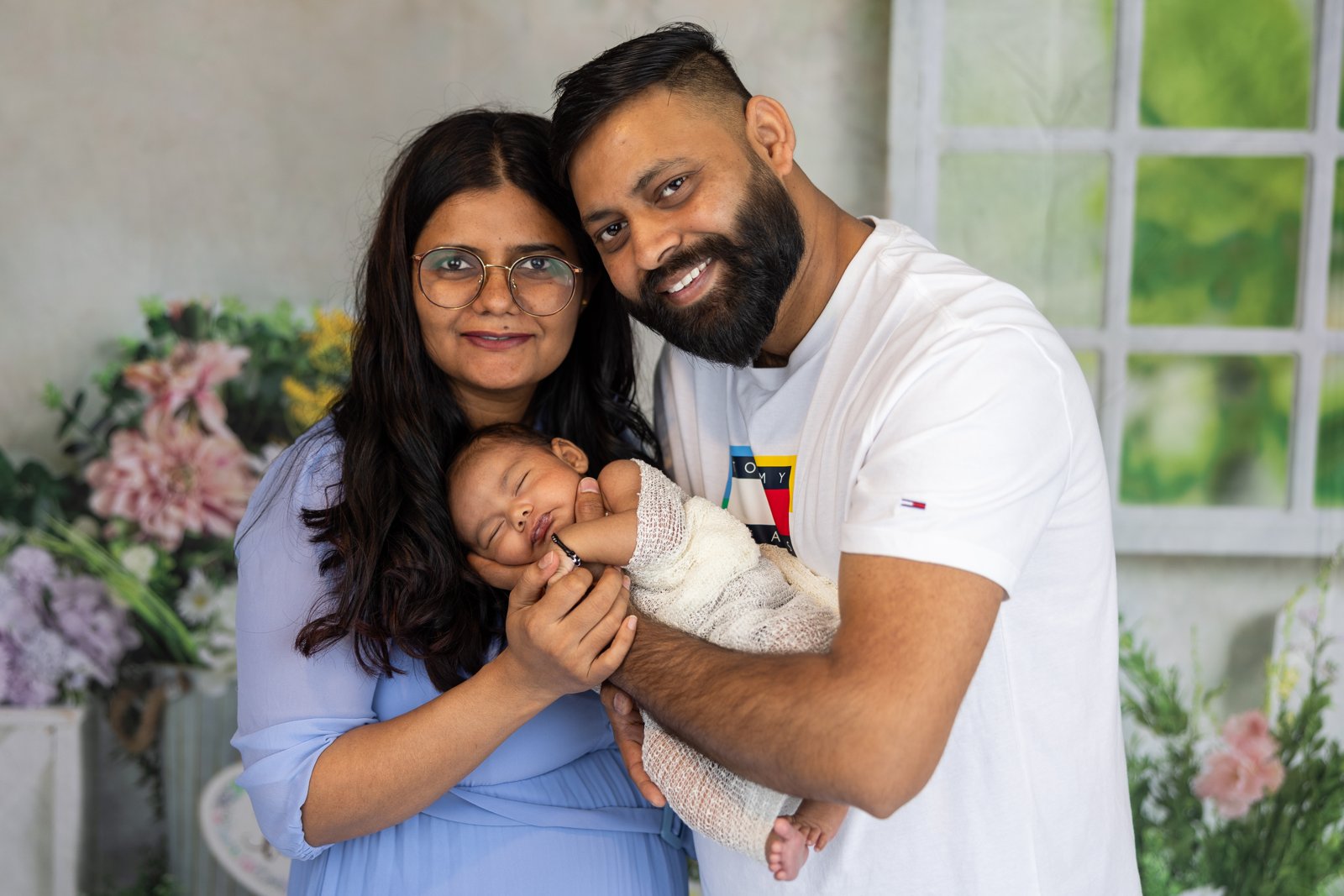 Parents smiling together while holding their newborn baby.