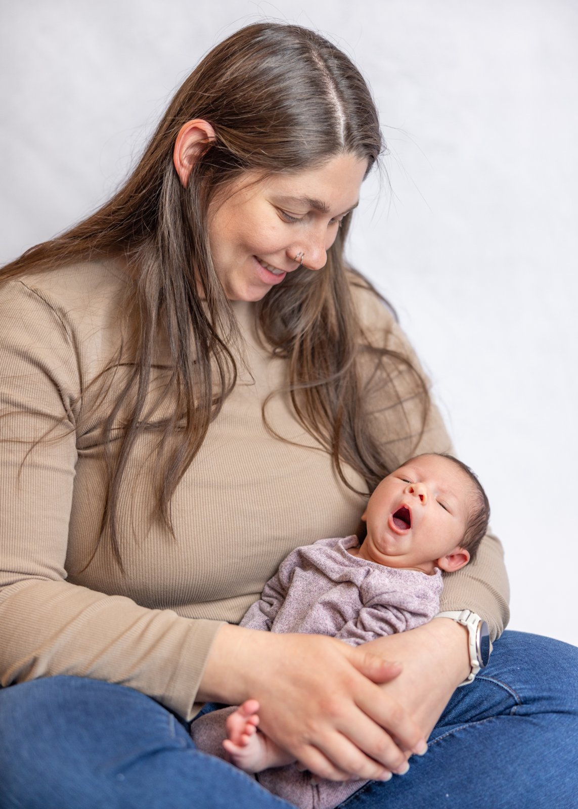 Mother looking down at her newborn baby in her arms.